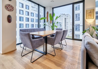 Immobilienfotograf München – Essbereich mit Holztisch, modernen Stühlen und Panoramafenstern