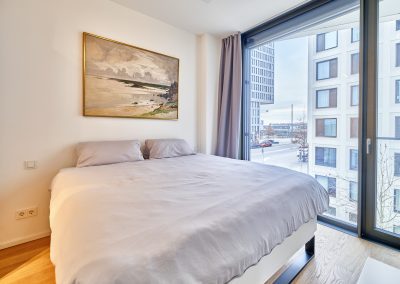 Immobilienfotograf München – Schlafzimmer mit Doppelbett, Wandkunst und bodentiefen Fenstern
