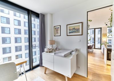 Immobilienfotograf München – Heller Raum mit Kommode, Wandkunst und bodentiefen Fenstern