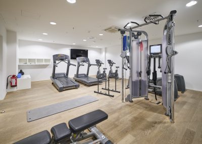Immobilienfotograf München – Moderner Fitnessraum mit hochwertigen Geräten und Holzboden